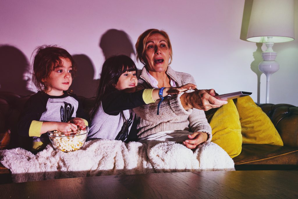 Dwie dziewczynki oglądają wraz z mamą telewizję  