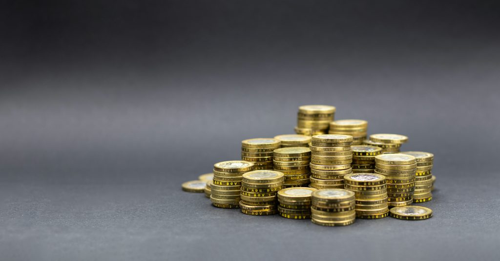 Ułożone w stosy monety na ciemnym tle symbolizujące oszczędzanie pieniędzy i zarządzanie finansami.